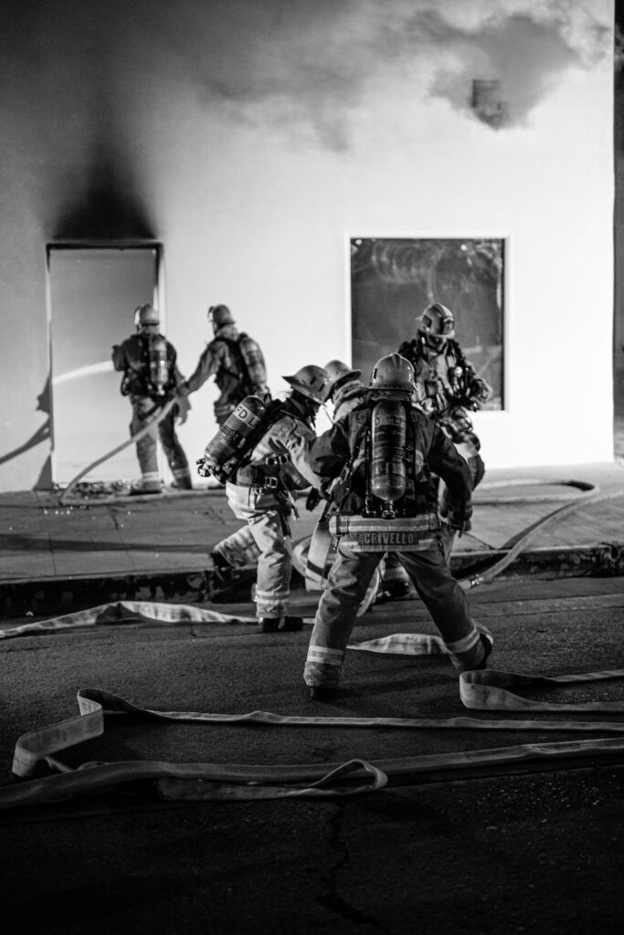 Firefighters advance hose lines during structure fire at night.