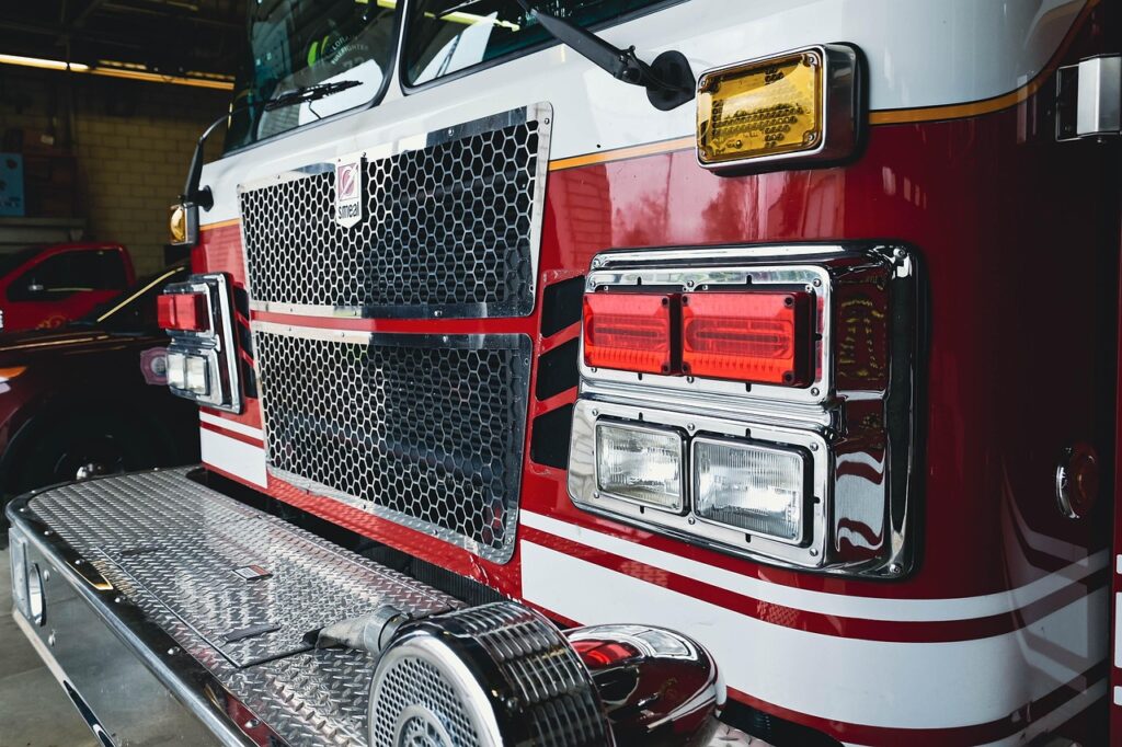 Close-up of a fire engine front grille and emergency lighting inside a fire station.