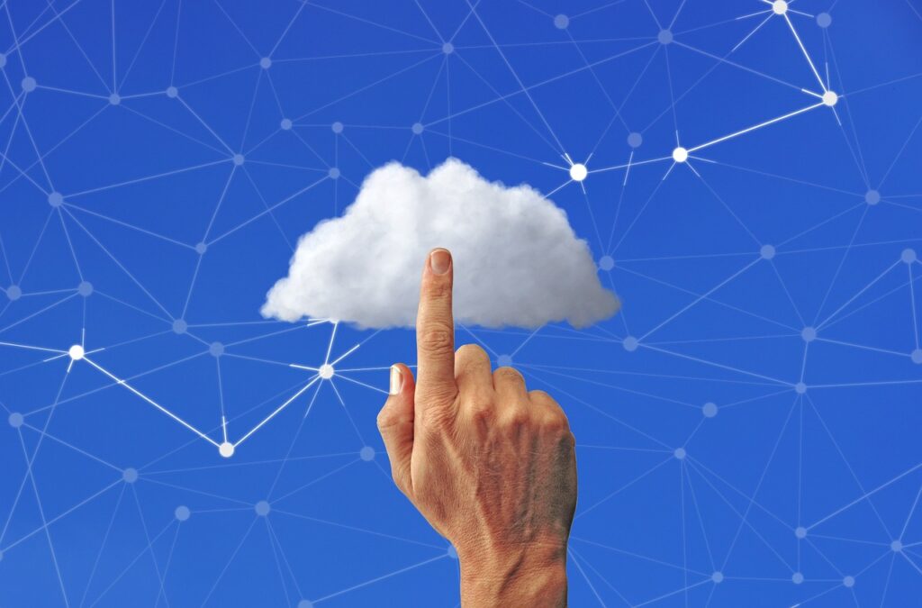 Hand pointing to a digital cloud with a network of connected nodes in the background.