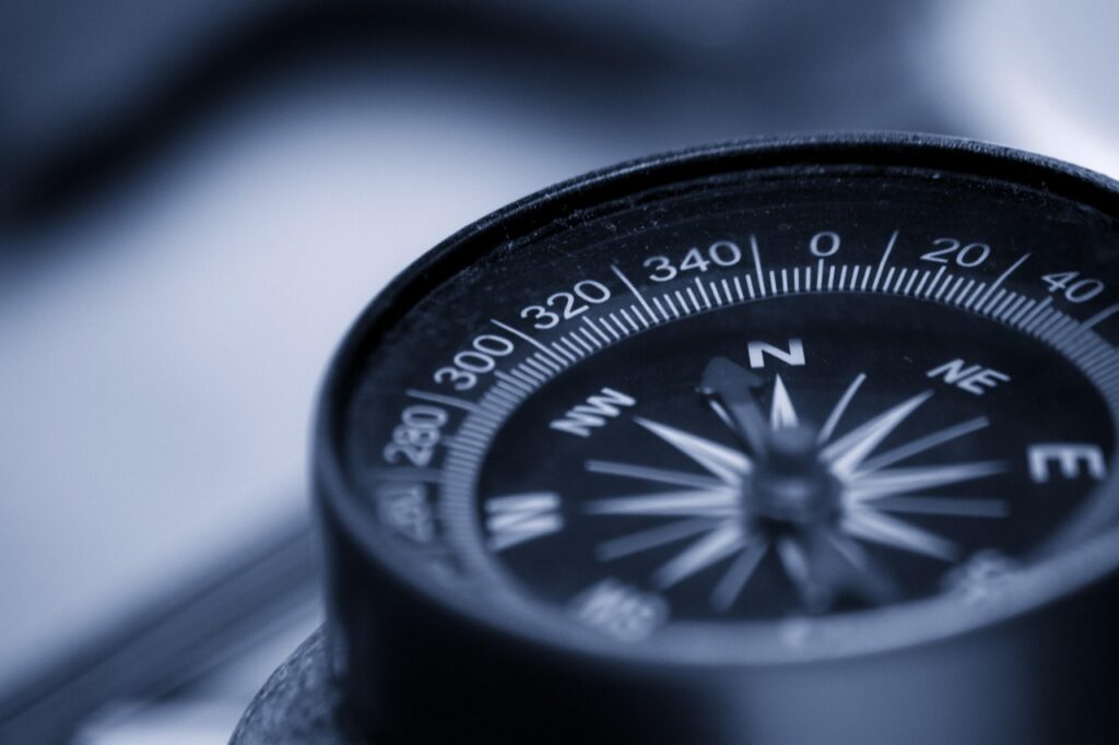 Close-up of a compass showing cardinal directions and degrees, symbolizing guidance and navigation.