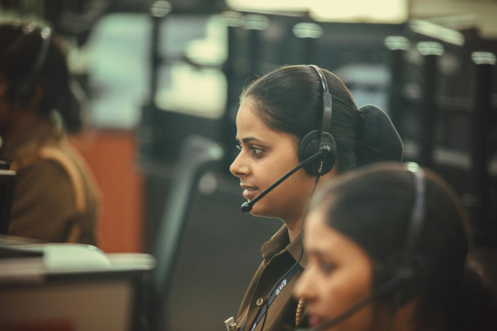 Female emergency dispatcher wearing a headset, focused on communication at a call center.