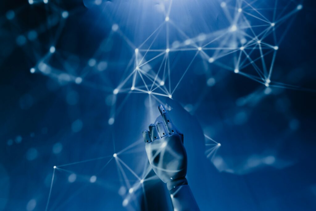 Robotic hand interacting with a glowing network of data nodes on a digital blue interface.