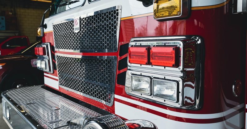Close-up of a fire engine front grille and emergency lighting inside a fire station.