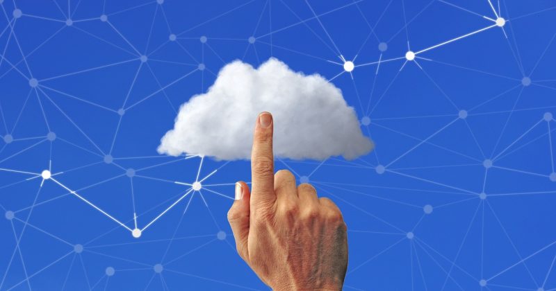Hand pointing to a digital cloud with a network of connected nodes in the background.