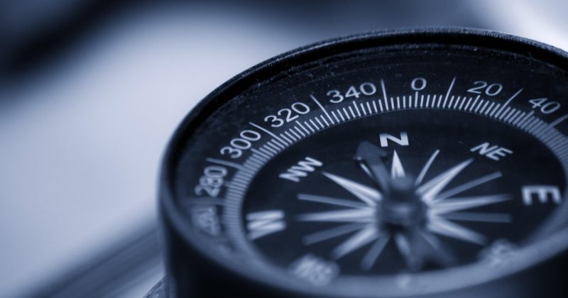 Close-up of a compass showing cardinal directions and degrees, symbolizing guidance and navigation.