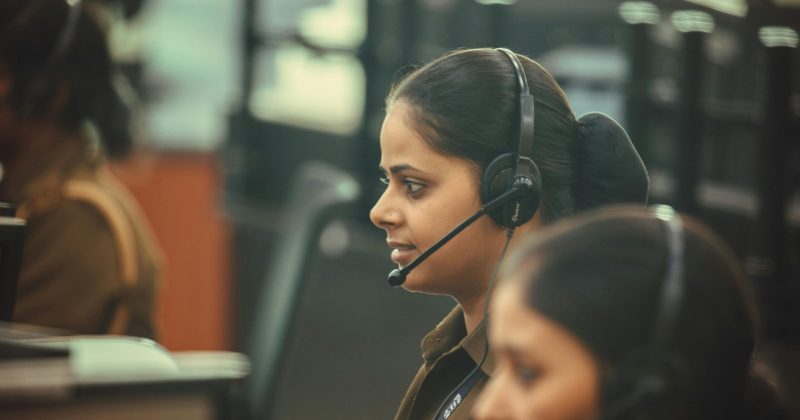 Female emergency dispatcher wearing a headset, focused on communication at a call center.