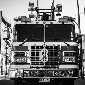 Front view of fire engine number 6 in urban setting, black and white